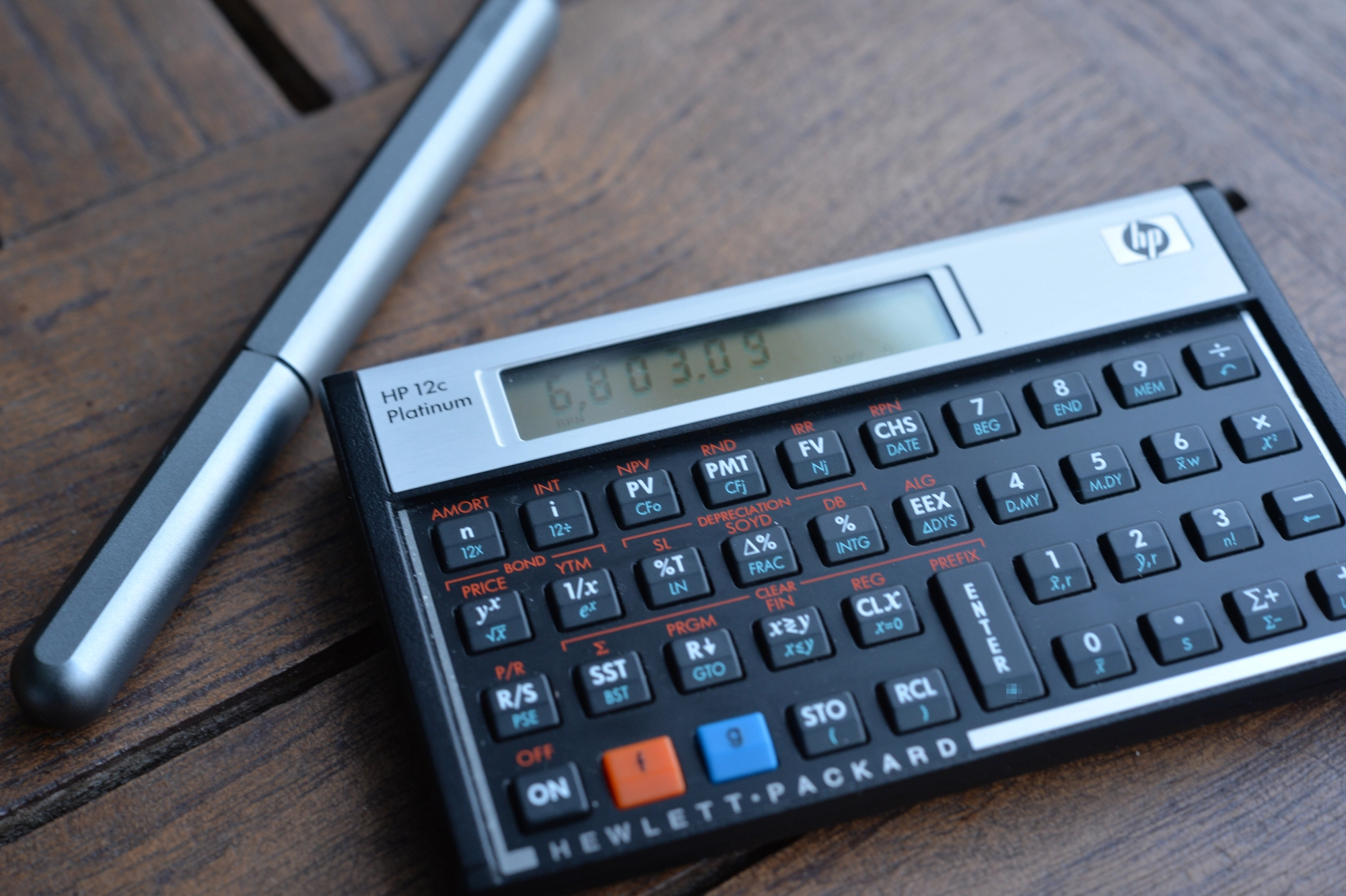 HP-12c platinum, a landscape financial calculator, with a silver Stilform fountain pen.